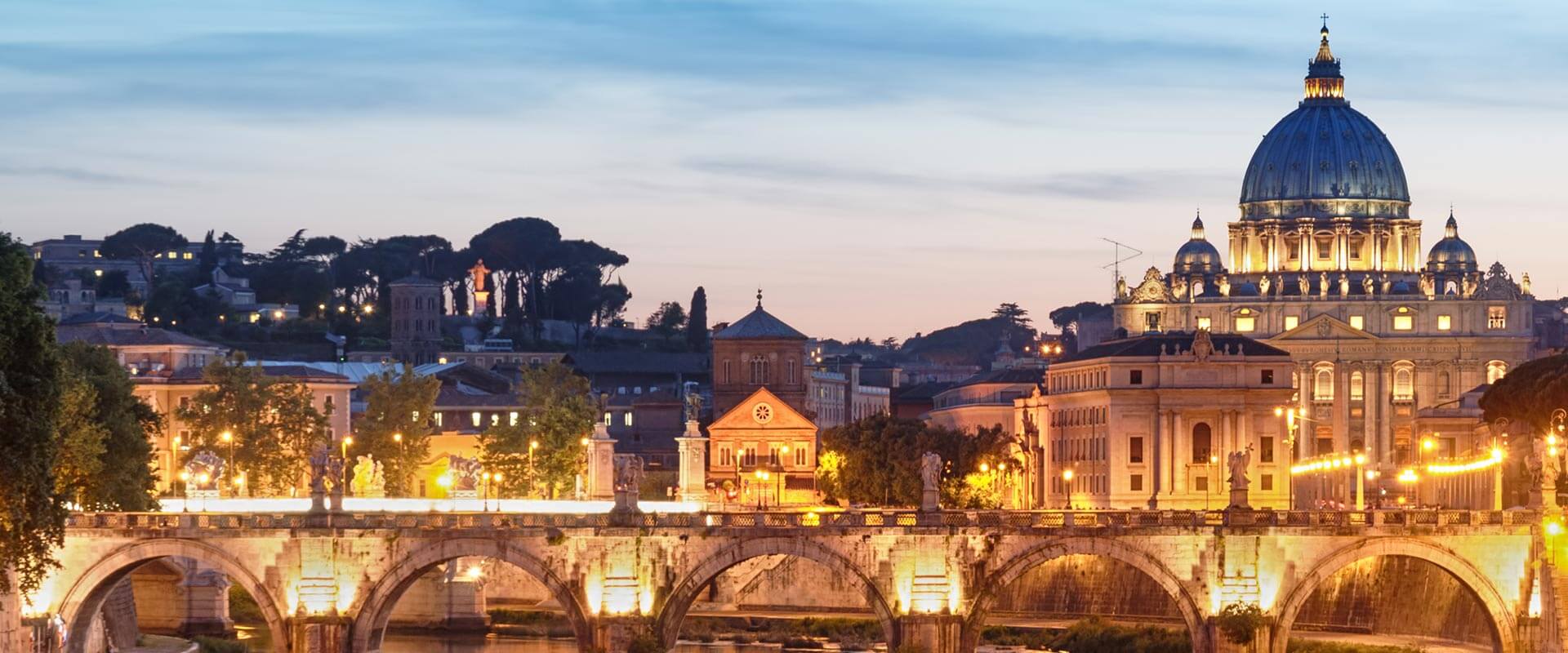 Vista notturna della Basilica di San Pietro dall'altro lato del ponte illuminato sul fiume Tevere a Roma.